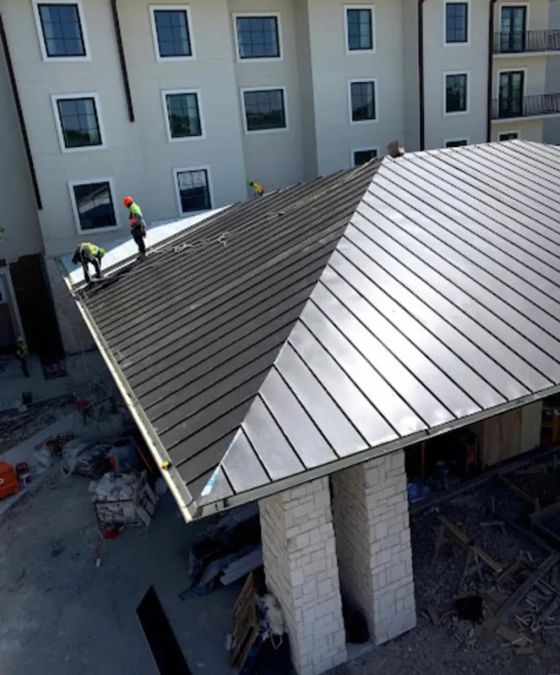 Crew installing standing seam metal roof panels on a commercial project in Avenal